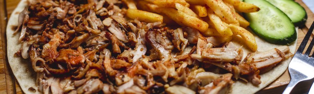 side view iskander doner on pita with french fries fresh cucumber and tomato side view iskander doner on pita with french fries fresh cucumber and tomato